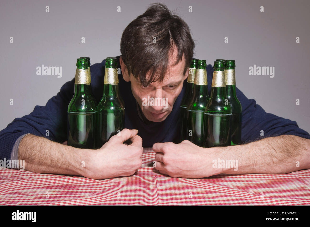 Man at table surrounded by beer bottles Stock Photo