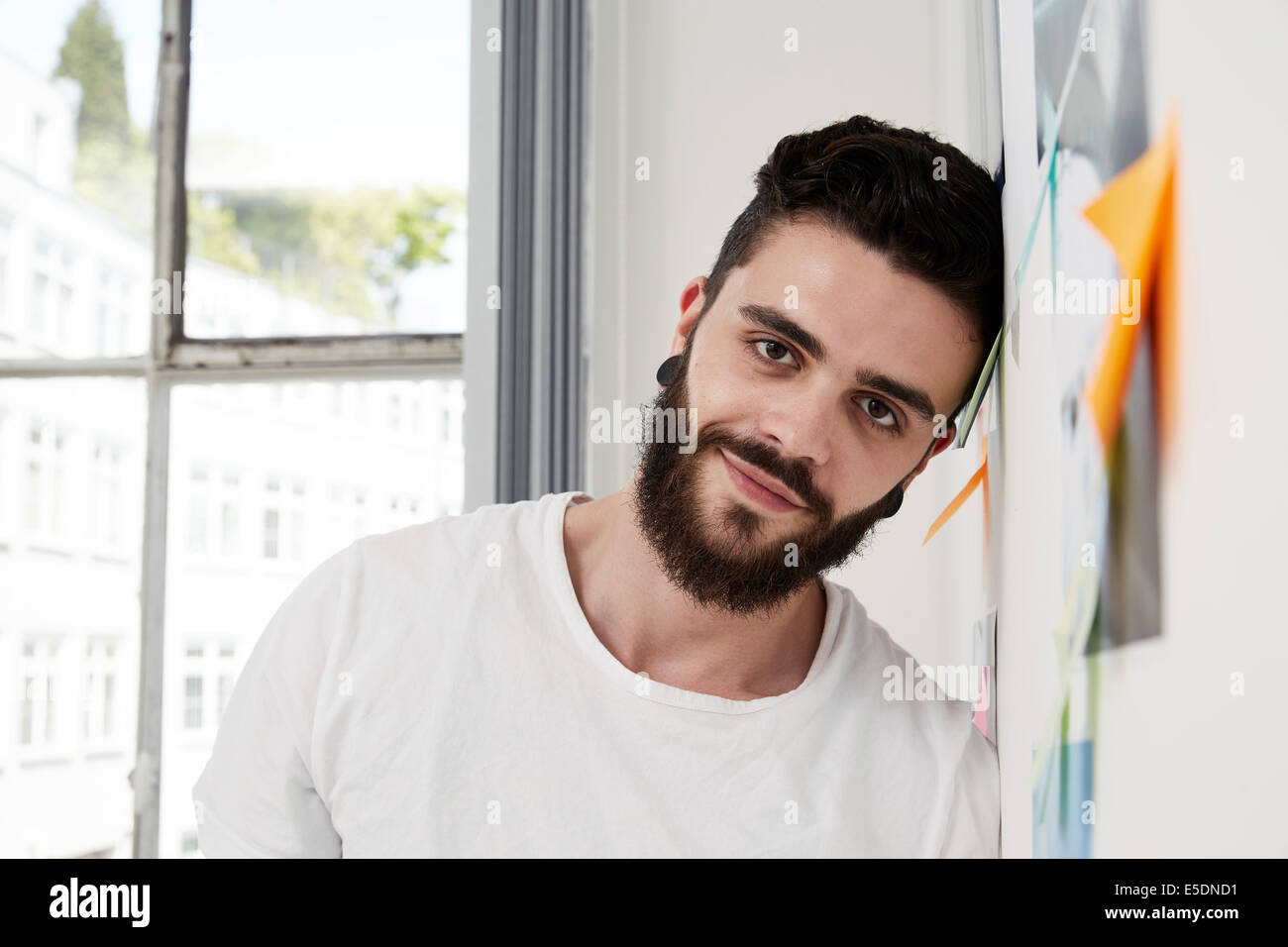 Smiling man leaning against wall with adhesive notes Stock Photo - Alamy