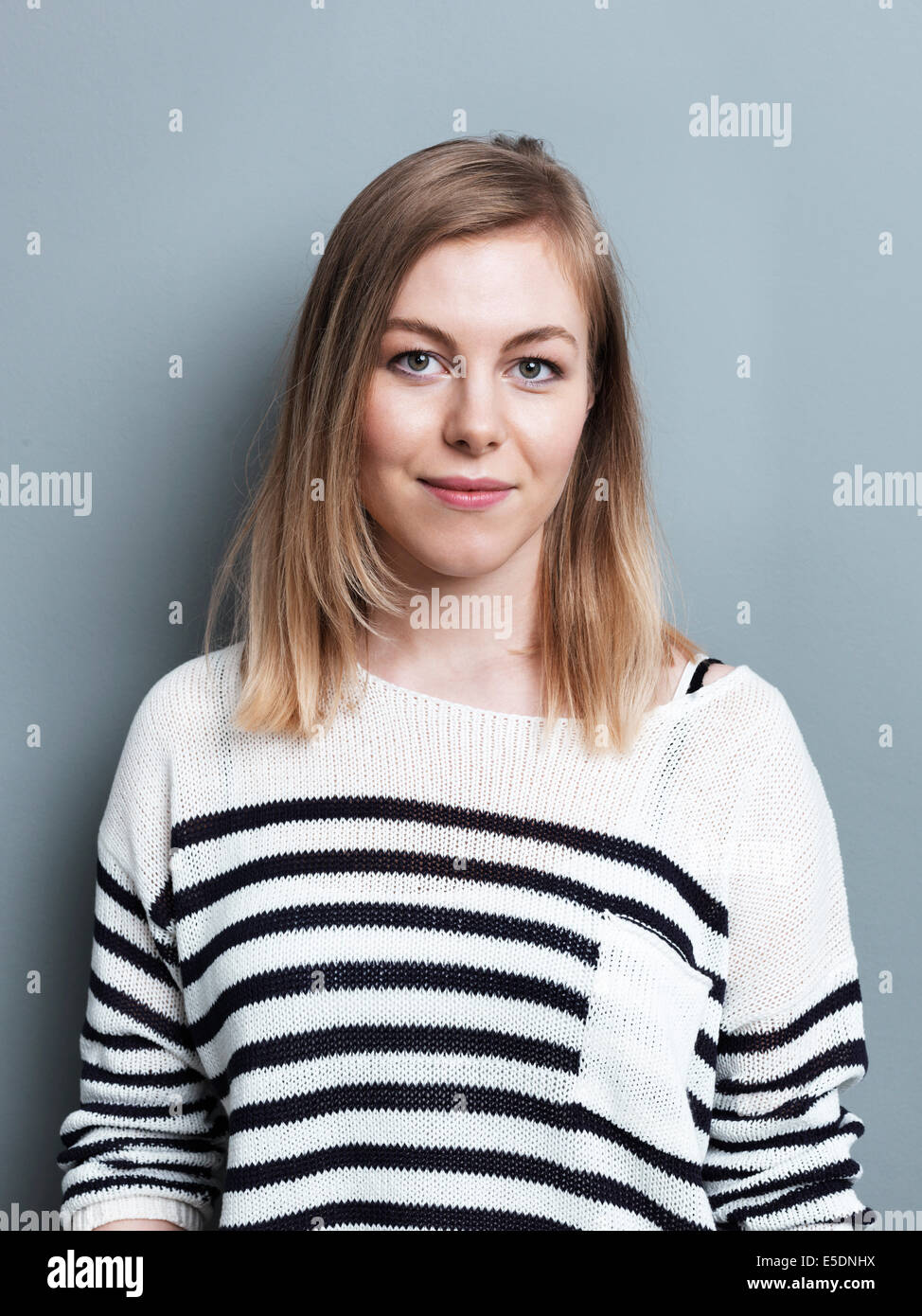 Portrait of blond woman in front of gray background Stock Photo