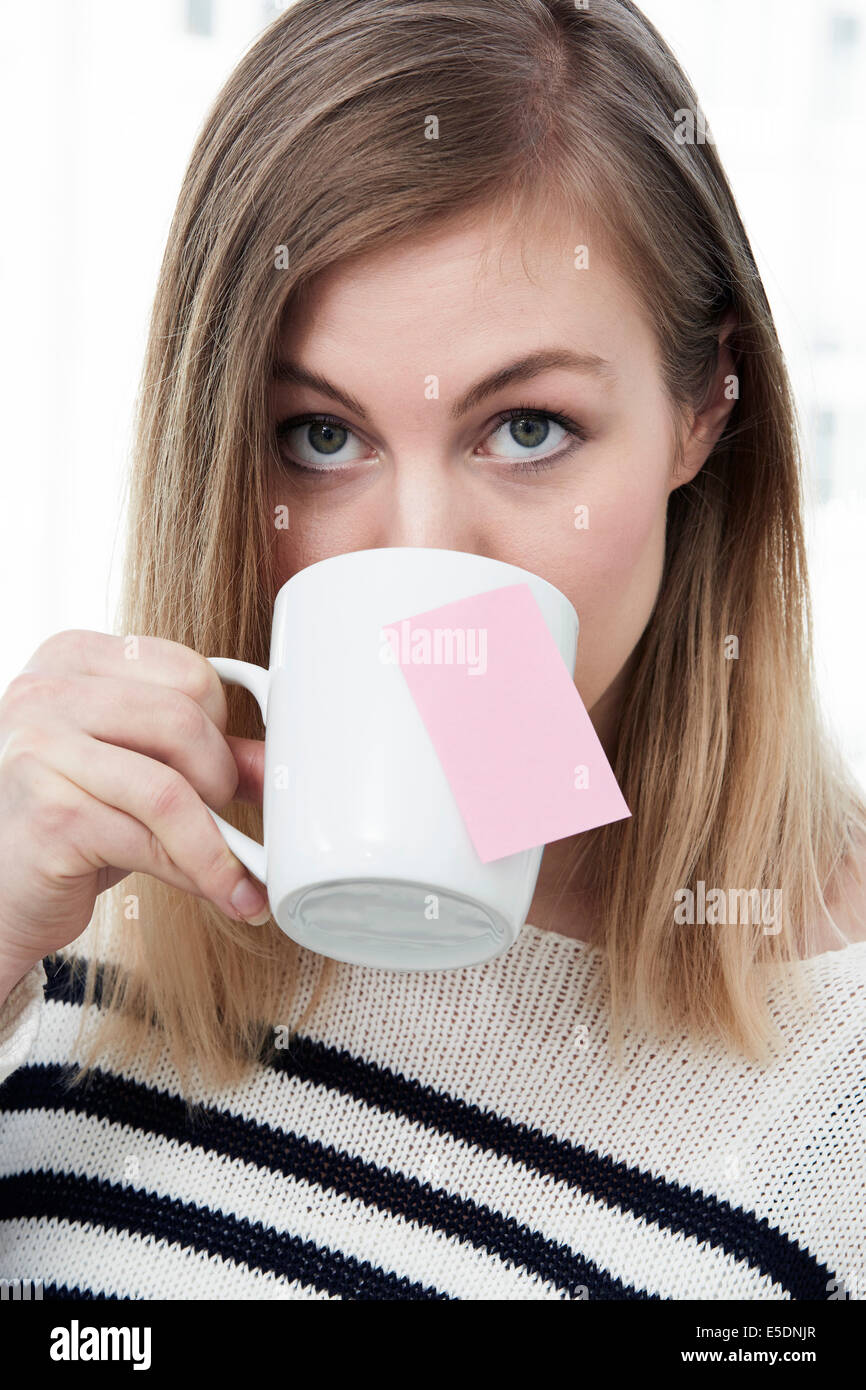 Woman drinking from cup with adhesive note Stock Photo