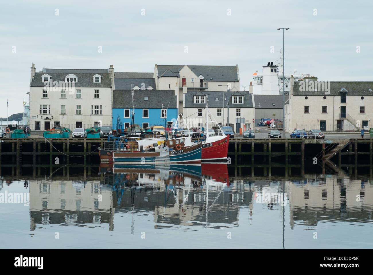 Fishing boats and harbourside houses reflected in the water, Stornoway, Outer Hebrides Stock Photo