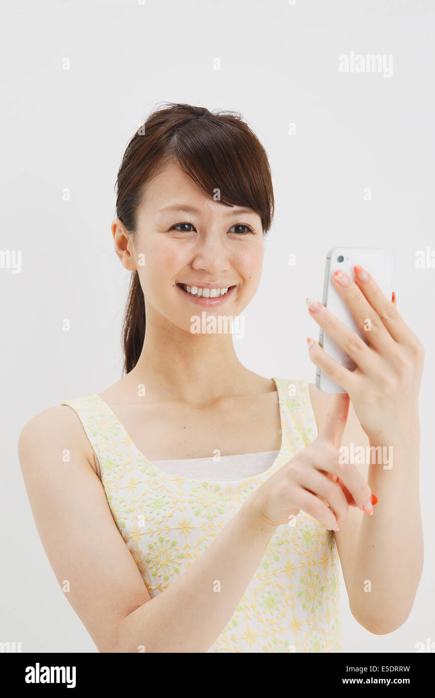 Japanese young woman in a one piece dress with smartphone against white background Stock Photo