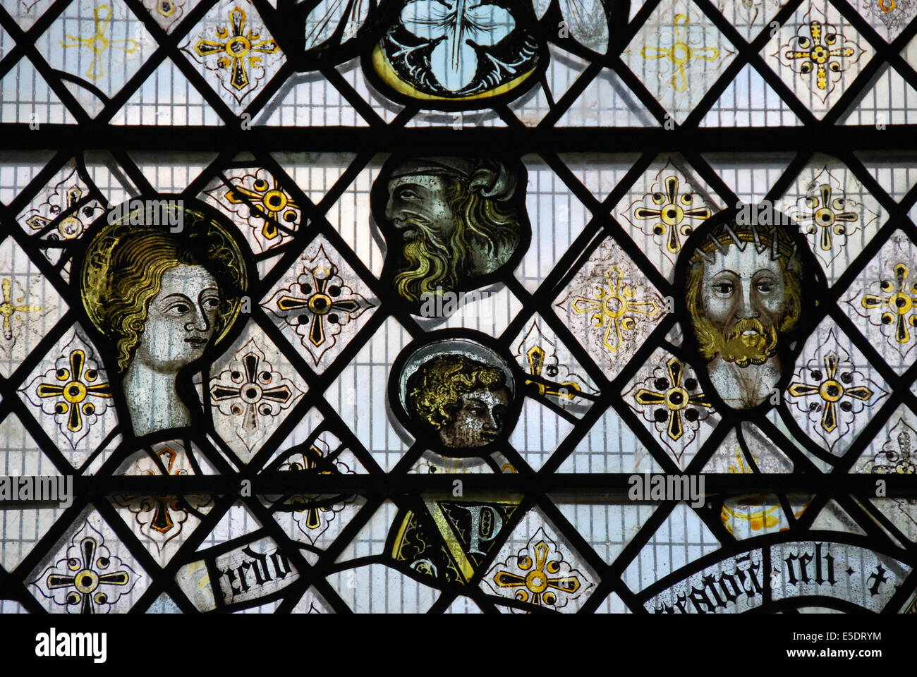 England. Ely Cathedral. Stained glass. man . woman. lead in diamond pattern . floral areas of pattern. yellow. black. writing. Stock Photo