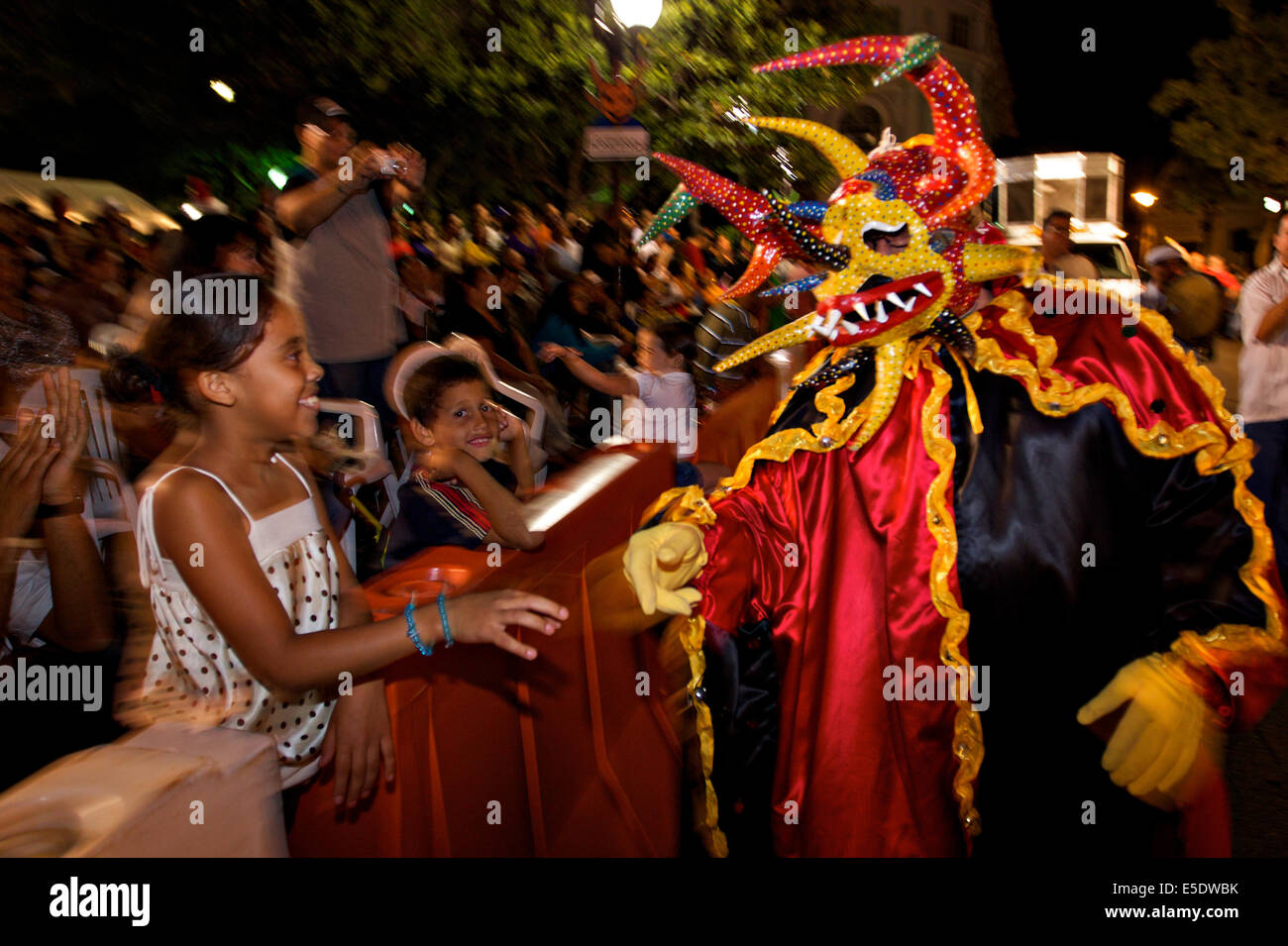 A costumed reveler called a vejigante greets children during the final night of parades during the Carnaval de Ponce February 21, 2009 in Ponce, Puerto Rico. Vejigantes are a folkloric character representing the devil. Stock Photo