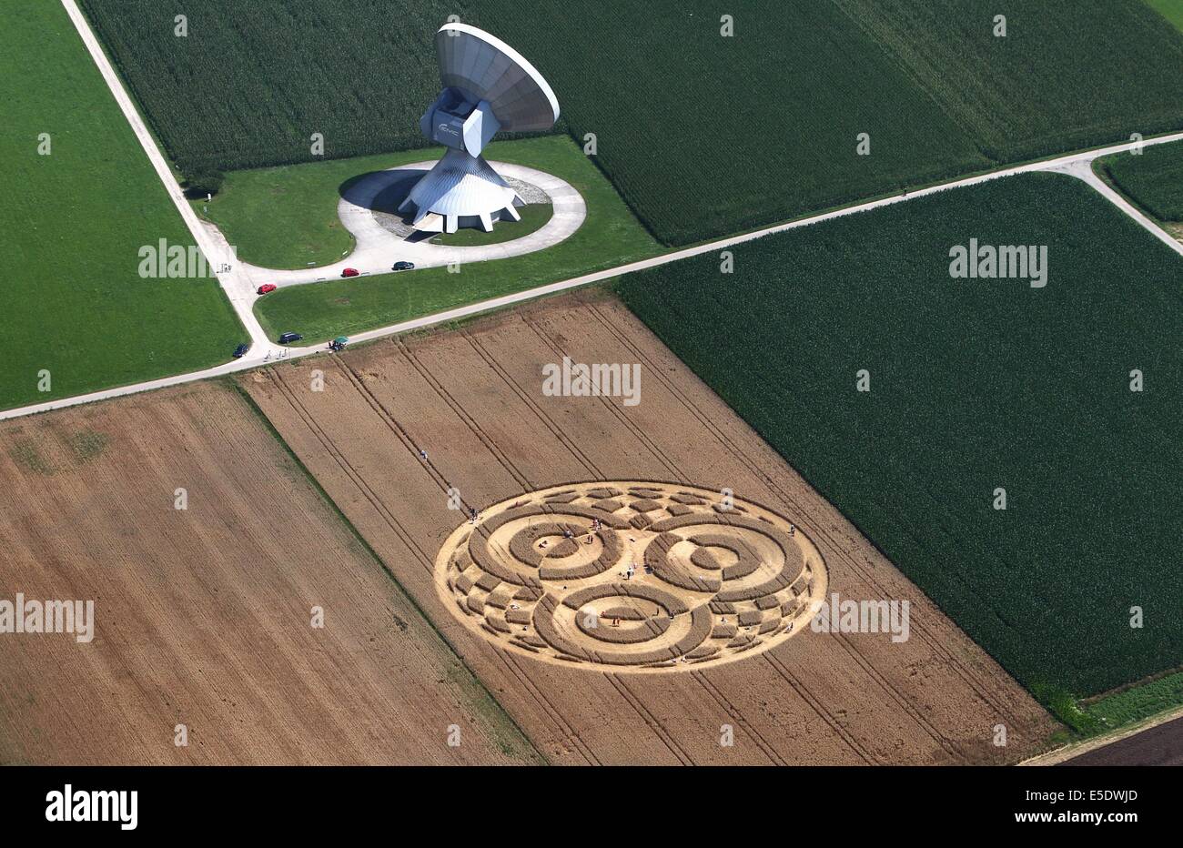 Raisting, Germany. 28th July, 2014. Visitors walks thorugh a crop circle in a wheat field next to an antenna of the earth station near Raisting, Germany, 28 July 2014. A balloonist had discovered the crop circle about a week ago. Photo: Karl-Josef Hildenbrand/dpa/Alamy Live News Stock Photo