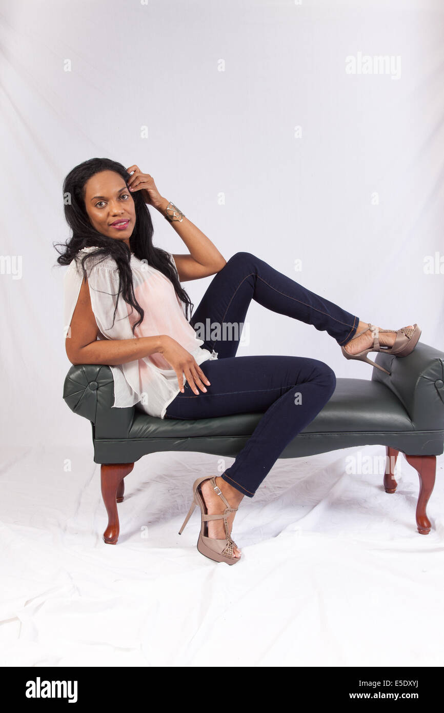 Pretty black woman sitting and looking at the camera with a happy, pleased smile Stock Photo
