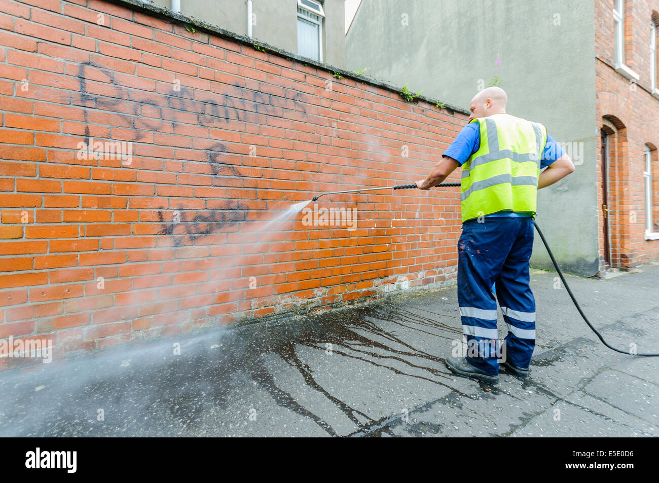 Belfast, Northern Ireland. 29th July, 2014. A council worker removes graffiti saying "Romanians R [sic] Housebreakers" spraypainted  on a wall in Belfast. Credit:  Stephen Barnes/Alamy Live News Stock Photo