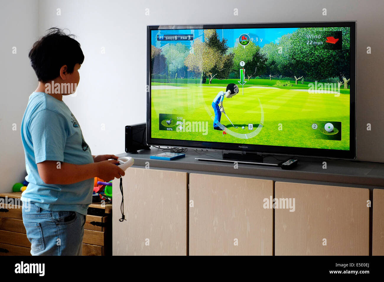 young boy playing in front of large screen with nintendo wii at home Stock Photo