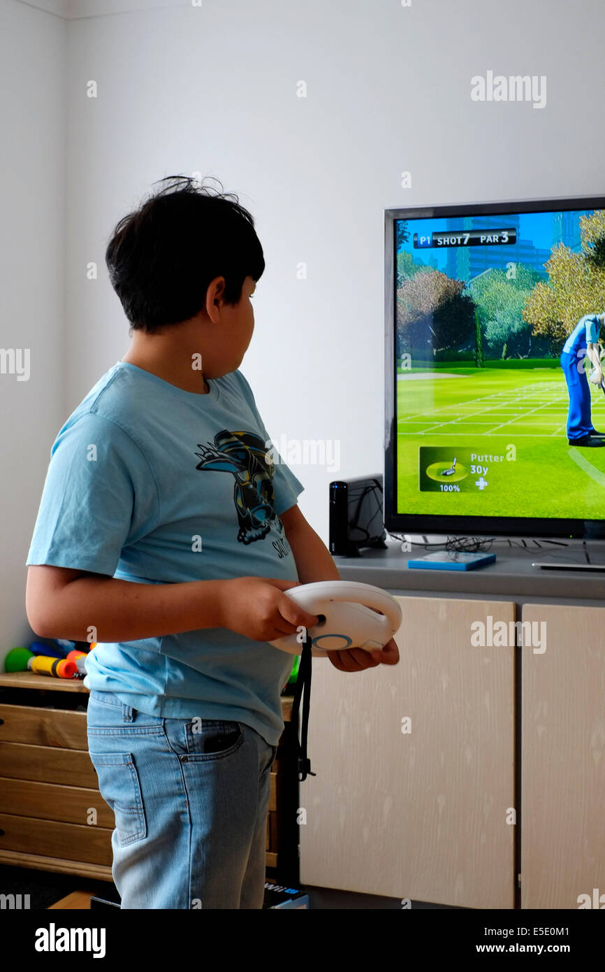 young boy playing in front of large screen with nintendo wii at home Stock Photo