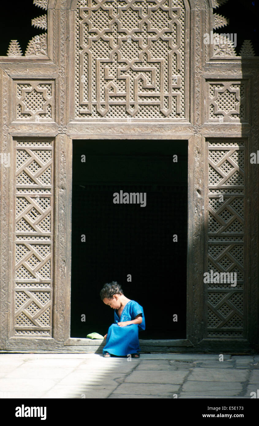 A young boy in a blue jubbah sitting in a door frame in the Al-Karaouine university, Medina, Fez, Morocco Stock Photo