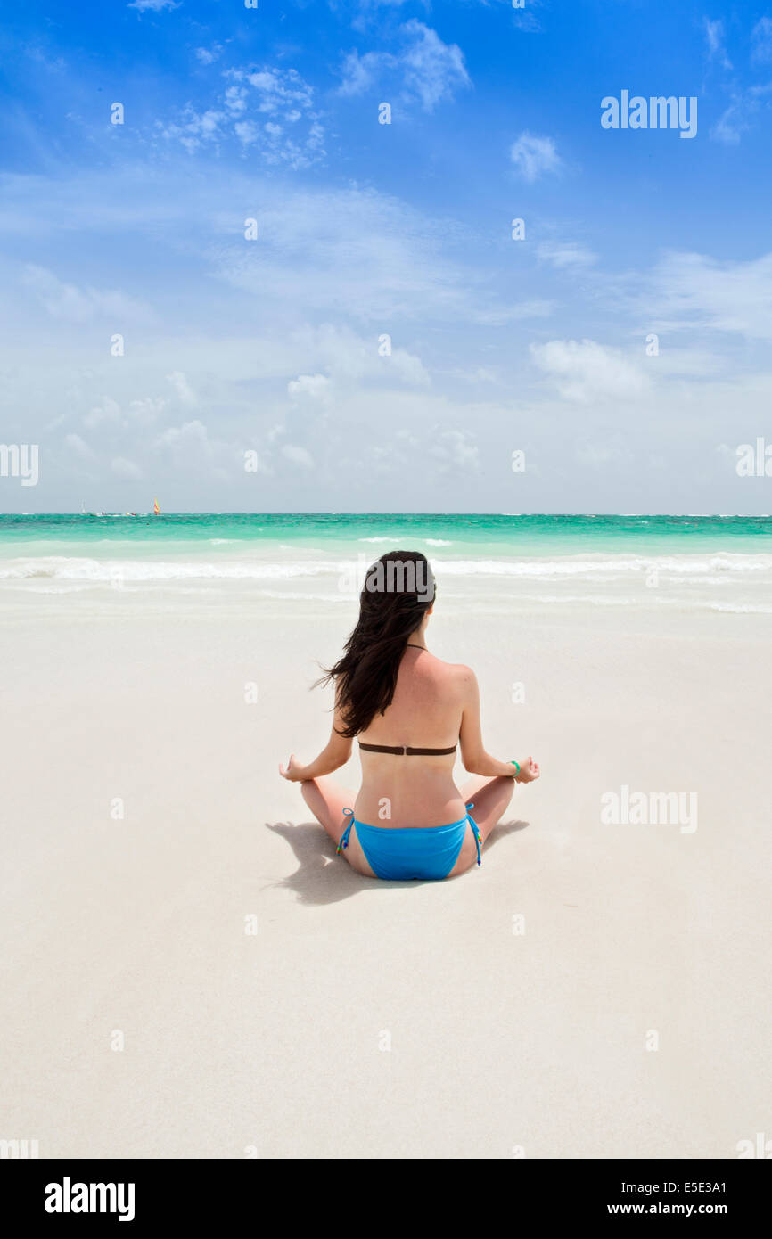 A young woman meditating on a beach in the Caribbean Stock Photo