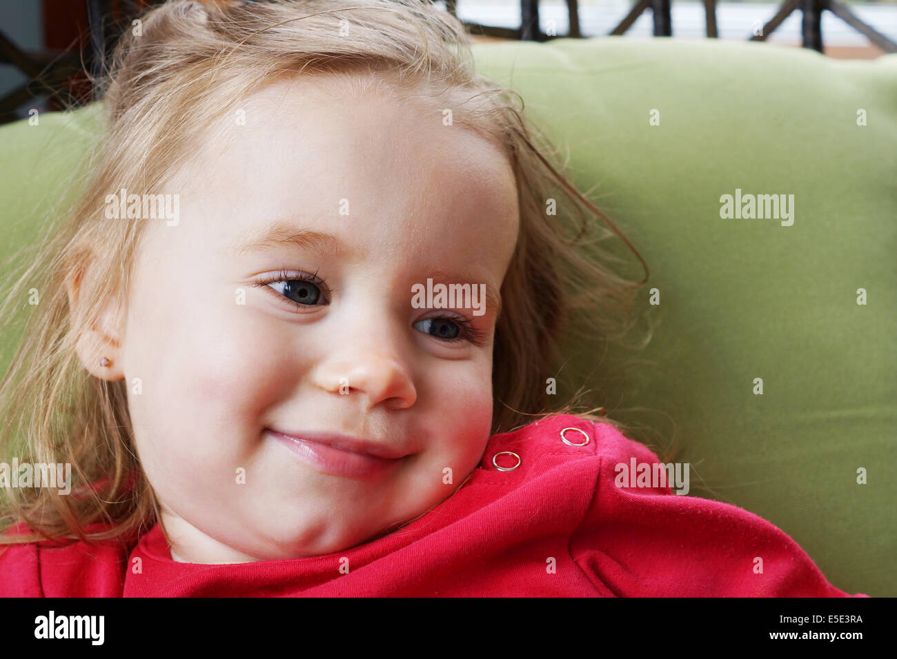 Portrait of a cute blond baby girl smiling, looking away. Stock Photo