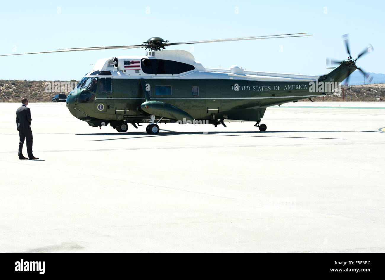July 23, 2014 - Los Angeles, California, U.S - Marine One --- Marine One on the tarmac at LAX on Wednesday July 23, 2014, taxis past a Secret Service Agent. Sikorsky's SH-3 Sea King helicopter has been in use by the US Marine Corps' HMX-1 squadron as the first choice for Marine One since not long after it was placed in service by the US Navy in 1961.  The familiar metallic green with white top Sea King is transported, along with the presidential limousine and other large equipment via a set of several C-17 Boeing Globemaster transport aircraft operated by the US Air Force.  US Navy specificati Stock Photo