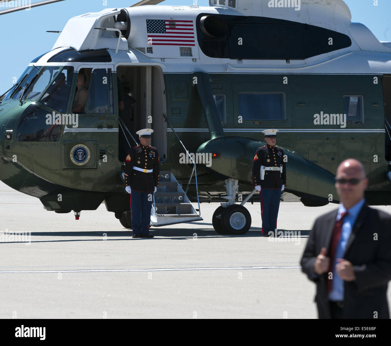 July 23, 2014 - Los Angeles, California, U.S - Marine One --- US Marines from HMX-1 hold their position alongside Marine One after receiving President Barack Obama on board at LAX on Wednesday July 23, 2014.  Sikorsky's SH-3 Sea King helicopter has been in use by the US Marine Corps' HMX-1 squadron as the first choice for Marine One since not long after it was placed in service by the US Navy in 1961.  The familiar metallic green with white top Sea King is transported, along with the presidential limousine and other large equipment via a set of several C-17 Boeing Globemaster transport aircraf Stock Photo
