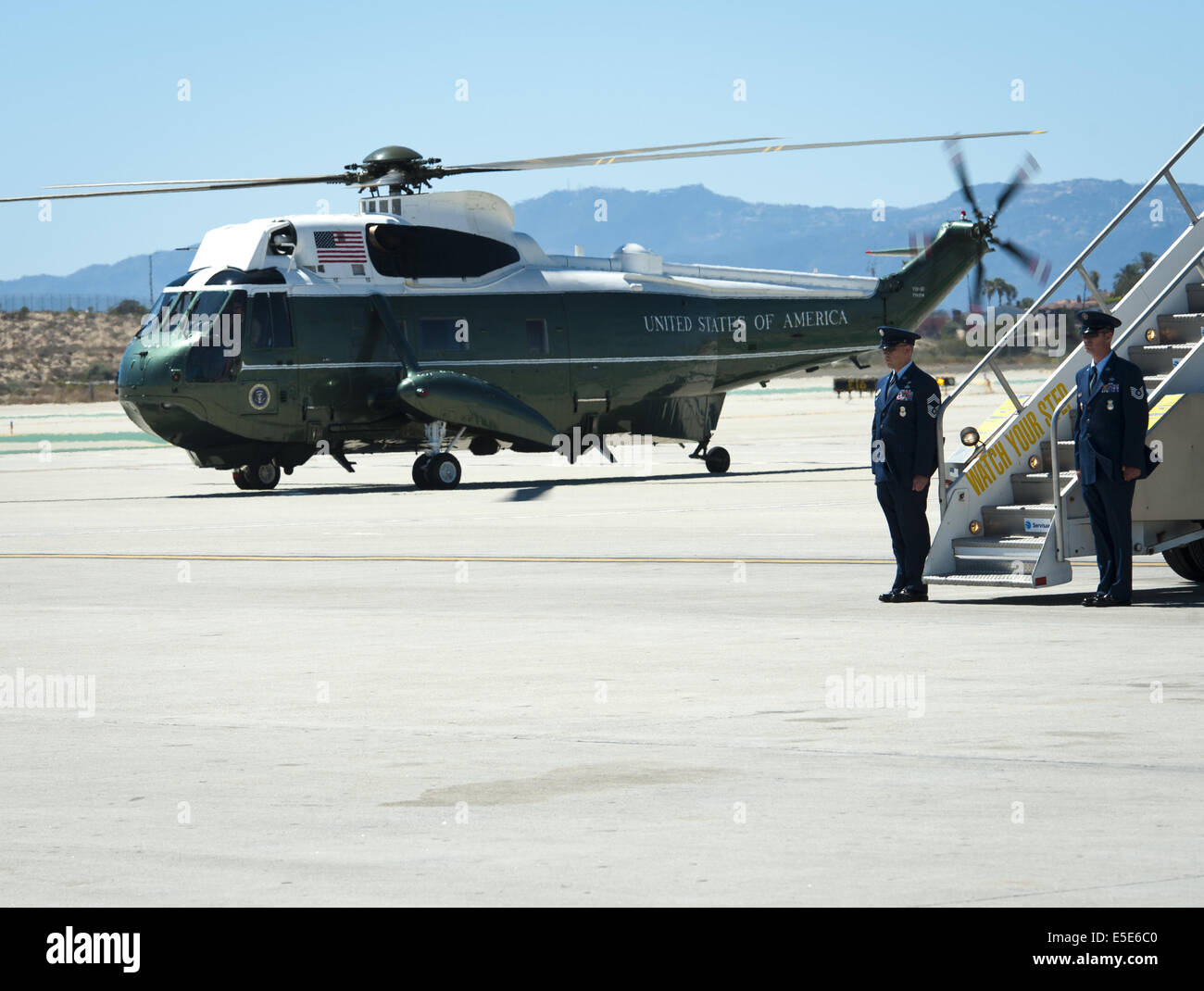 July 23, 2014 - Los Angeles, California, U.S - Marine One --- A Marine One Escort warms up along side Air Force One after the arrival of President Obama at LAX on Wednesday July 23, 2014. Sikorsky's SH-3 Sea King helicopter has been in use by the US Marine Corps' HMX-1 squadron as the first choice for Marine One since not long after it was placed in service by the US Navy in 1961.  The familiar metallic green with white top Sea King is transported, along with the presidential limousine and other large equipment via a set of several C-17 Boeing Globemaster transport aircraft operated by the US  Stock Photo