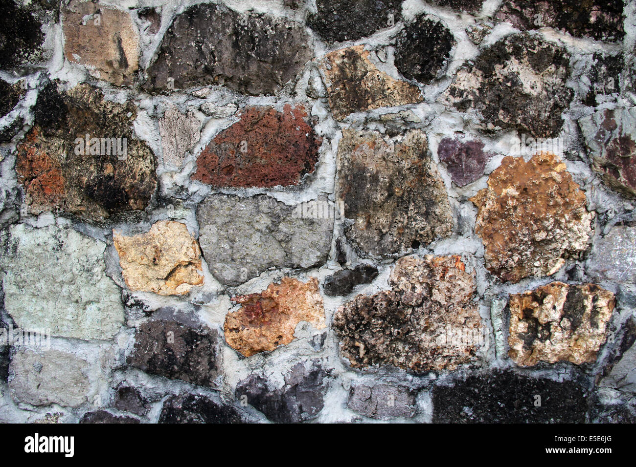 Background textured wall with unusual stones of various colors, shapes, textures and sizes found in Antigua Barbuda in the Carib Stock Photo
