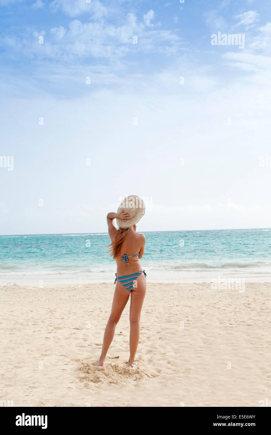 A beautiful young woman in a bikini and beach hat on a beach Stock Photo