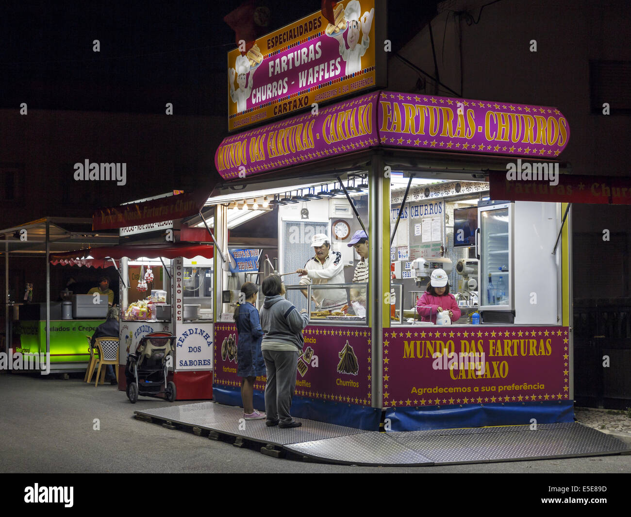 Youngsters buying doughnuts from a brightly lit food kiosk Portugal Stock Photo