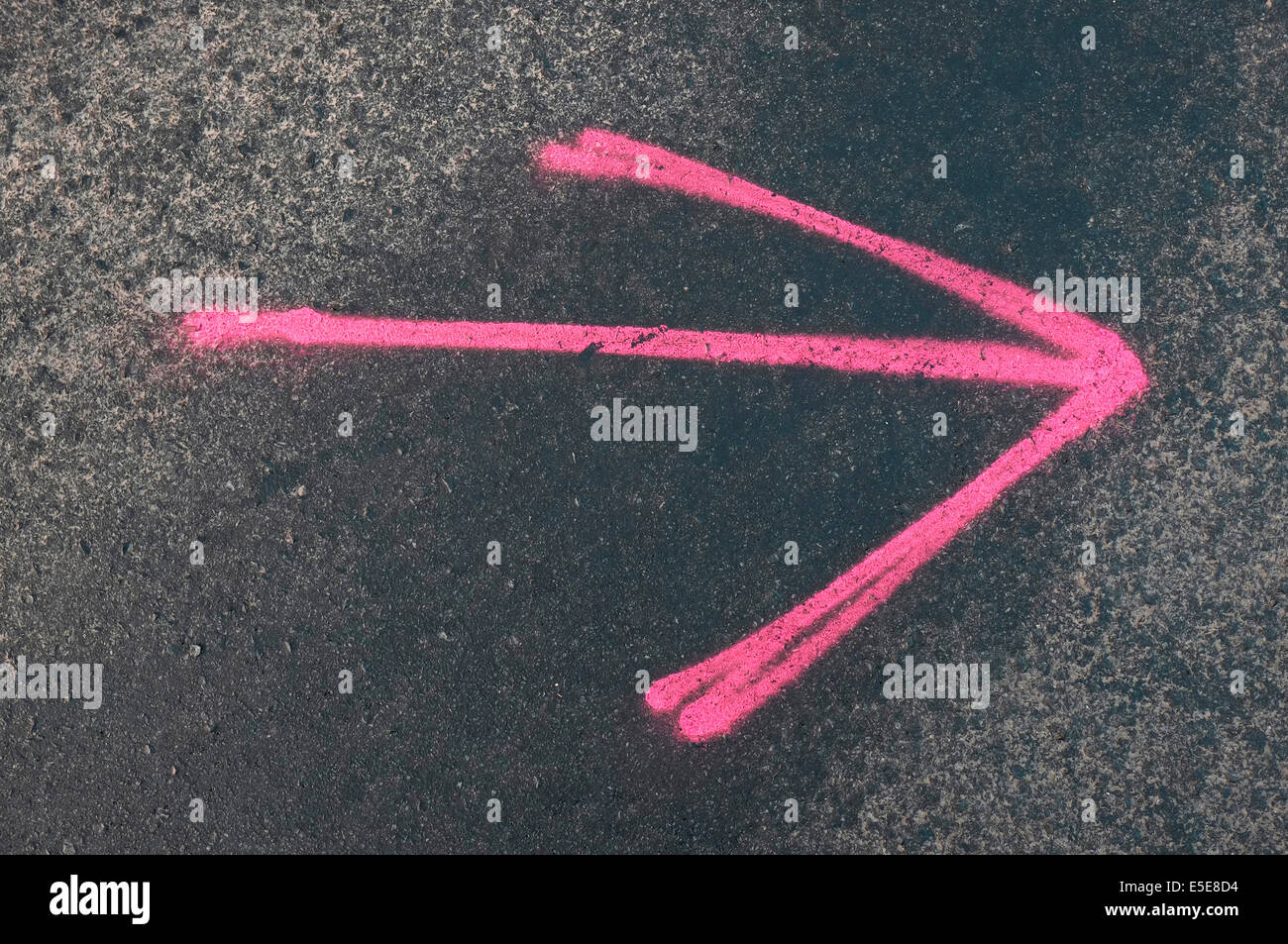 pink arrow on dark tarmac road background Stock Photo