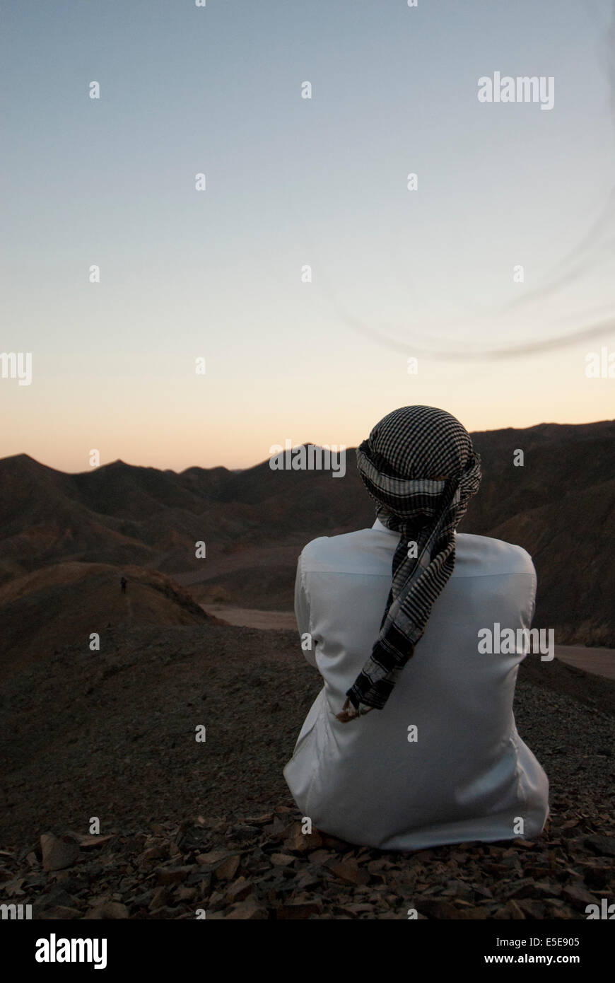 Bedouin man looks out over the desert during the sunset. Stock Photo