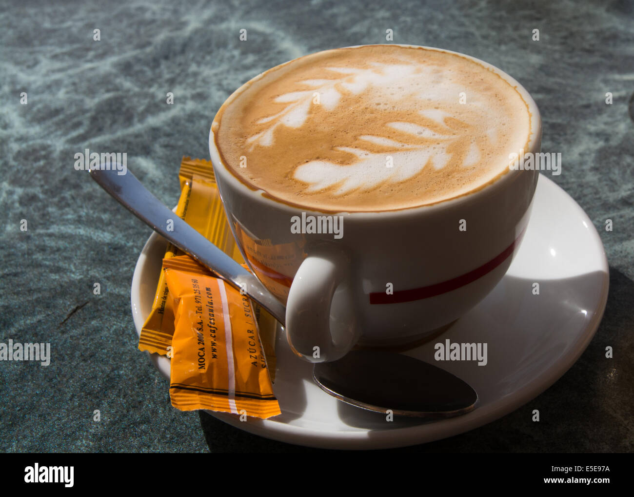 Cafe con leche with pattern and sugar or cookies contained in wrap. Stock Photo