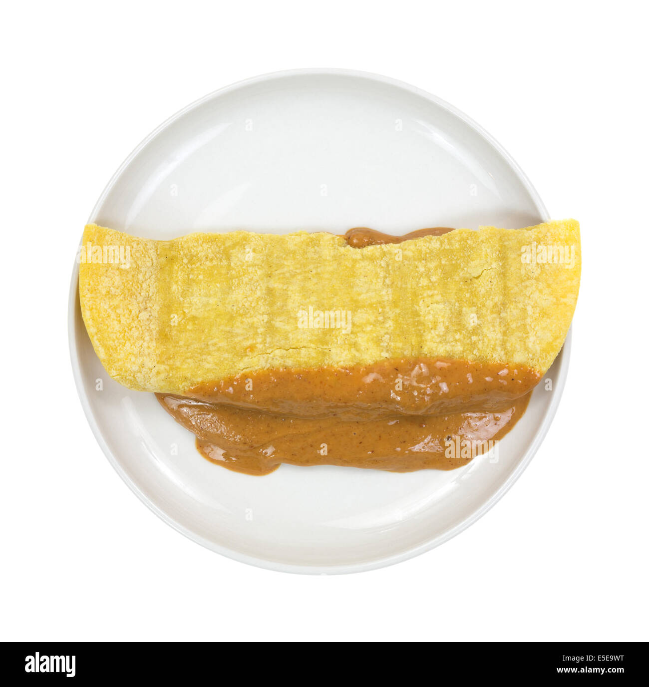 Top view of a small plate with a folded corn tortilla filled with peanut butter. Stock Photo