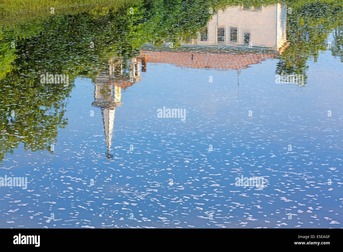 A reflection of a spired church on rippling water with foam flecks in Frankfort, Maine. Stock Photo