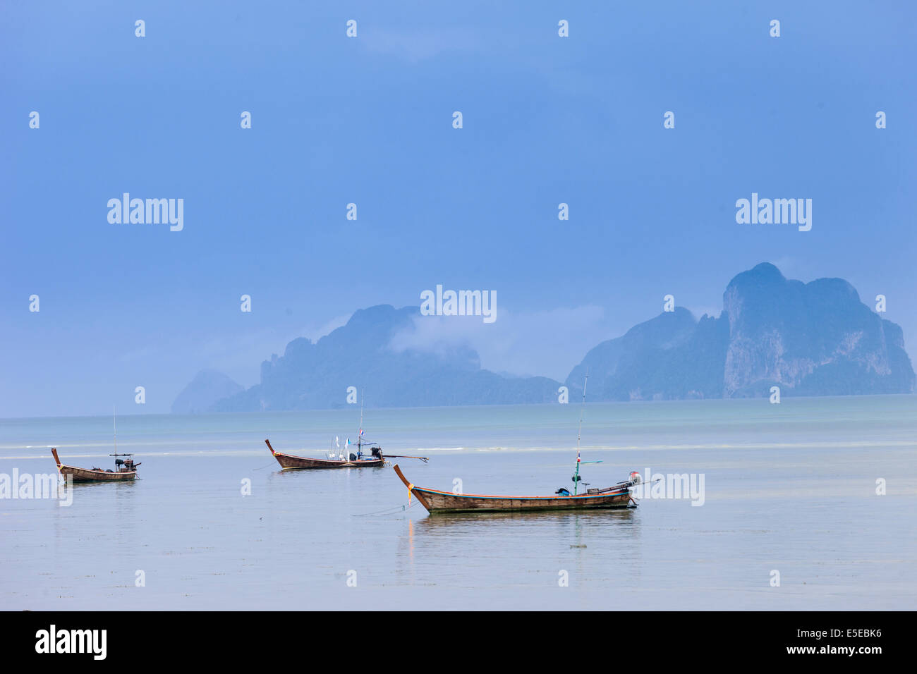 Long tail boats moored in Trang under heavy storm clouds, Thailand Stock Photo
