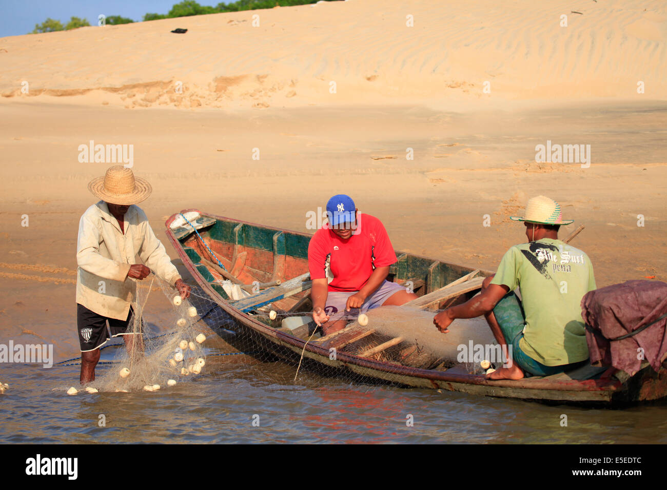 Fishermen reeling in a net into a wooden boat, Delta do Parnaiba, Brazil Stock Photo