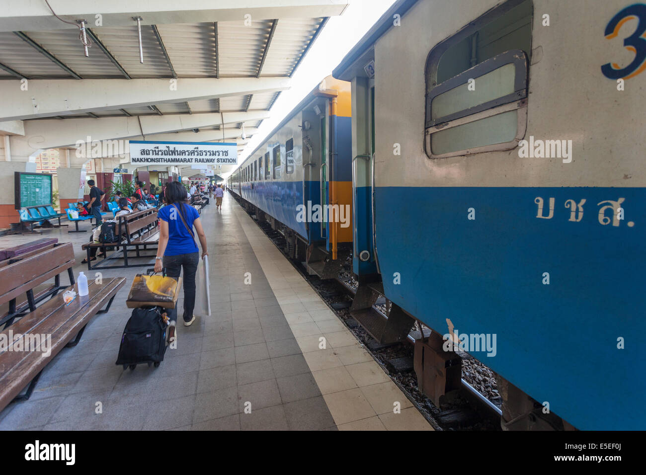 A passenger pulling luggage to a train at Hualamphong Railway station Bangkok Thailand Stock Photo