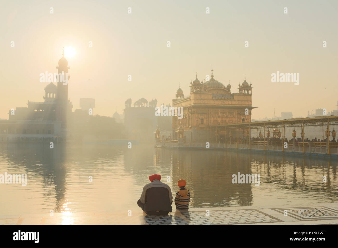 A father and son praying at the Sikh Golden Temple in Amritsar, Punjab, India Stock Photo