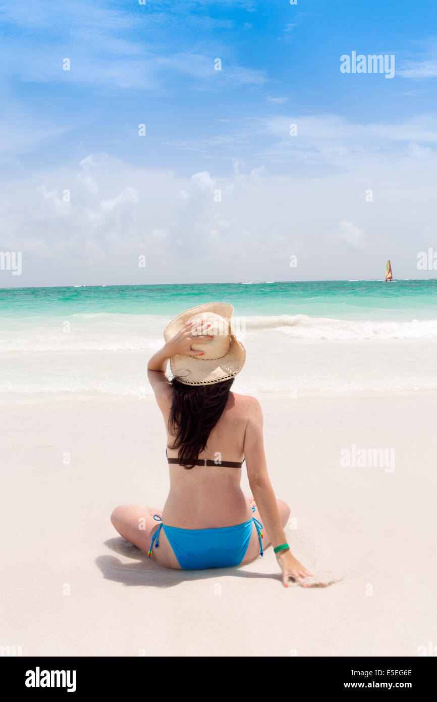 A young woman sitting on a beach in the Caribbean Stock Photo