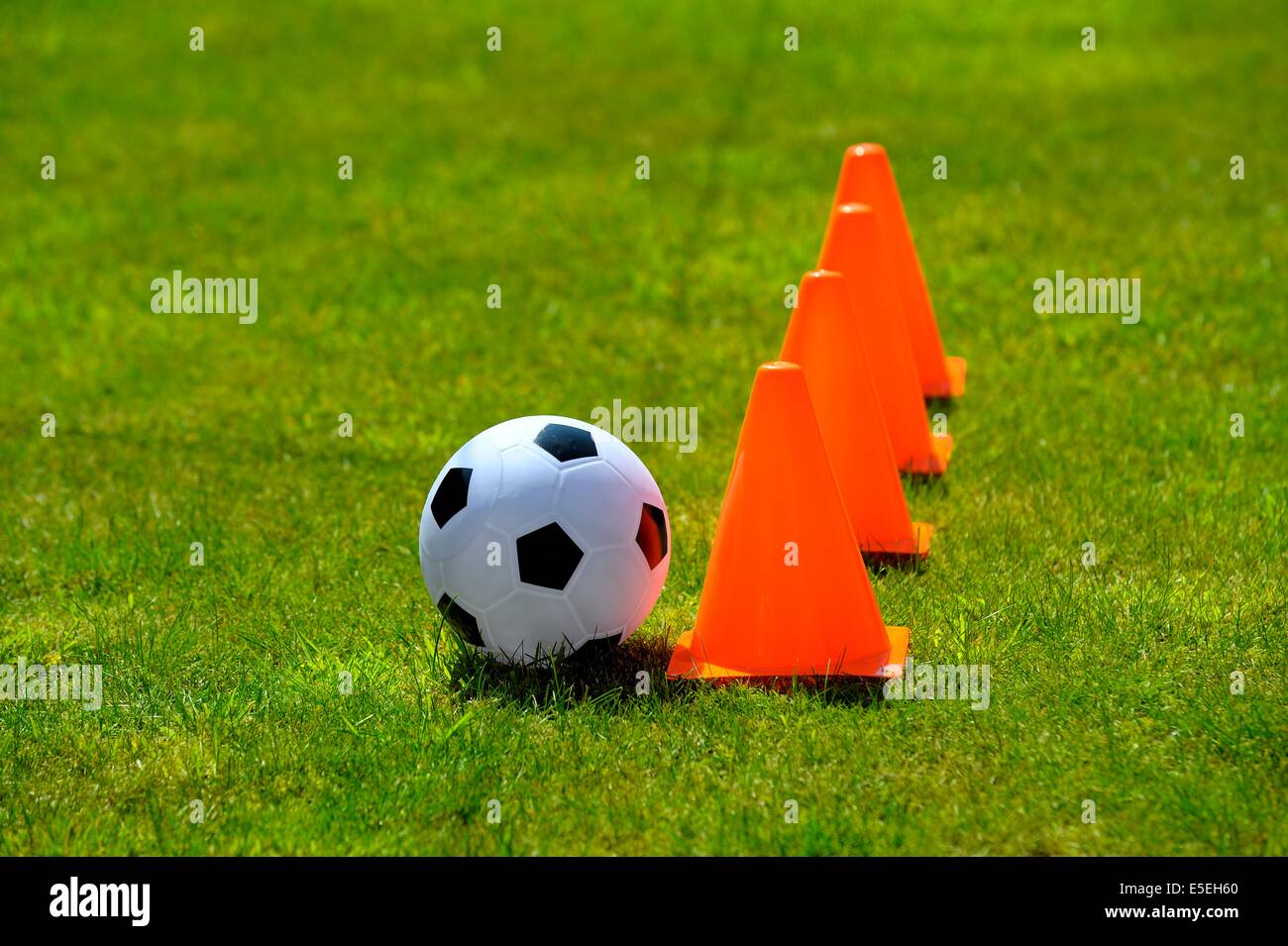Orange cones and a football in a garden on a sunny day uk Stock Photo