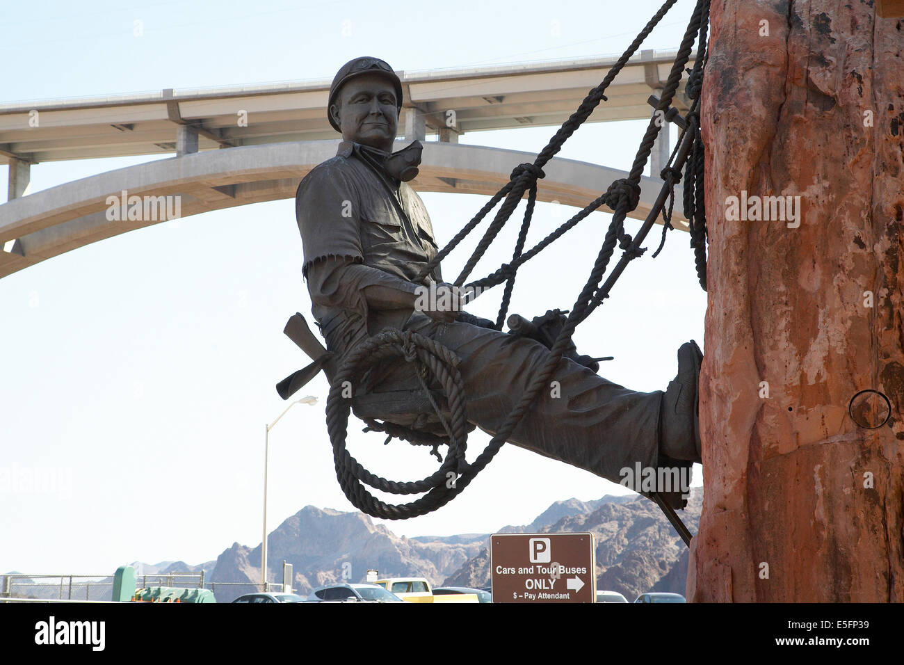 Statue of dam worker hanging on cliff at Hoover Dam, Nevada with the Mike O'Callaghan-Pat Tillman Memorial Bridge behind. Stock Photo