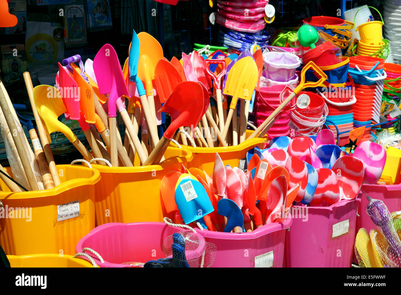 A shop display of brightly coloured pink and yellow buckets and spades. Stock Photo