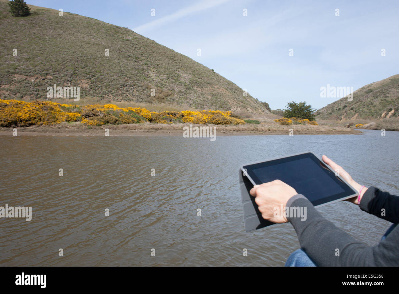 Man using tablet by river Stock Photo