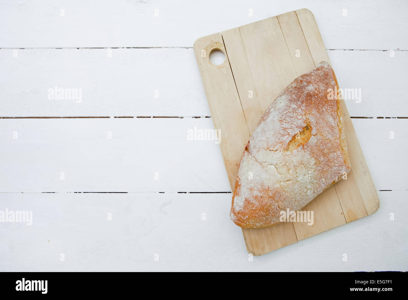 Loaf of bread on a cutting board and white wood table Stock Photo - Alamy
