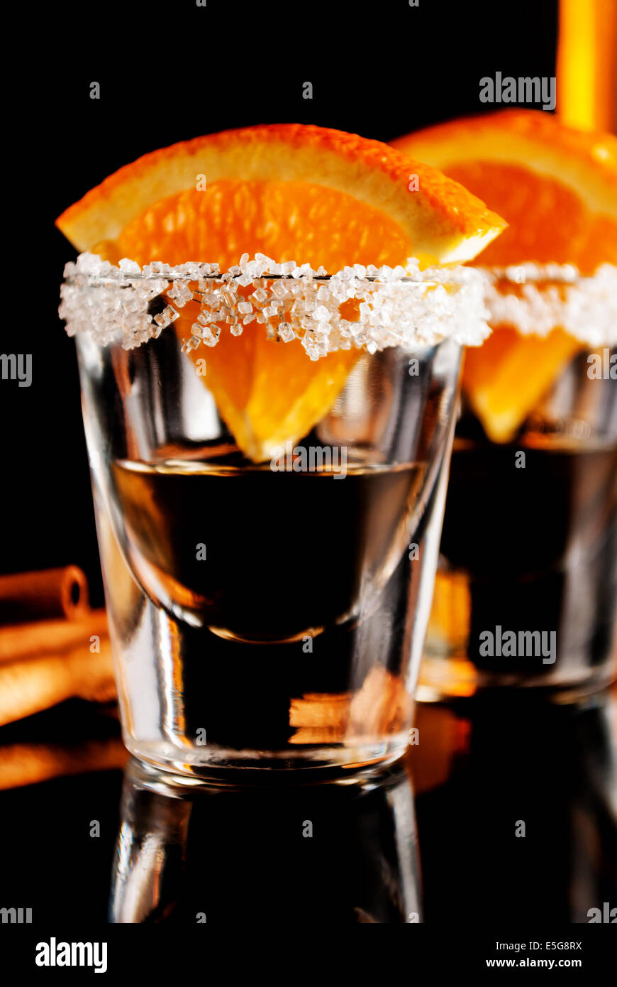 Gold tequila with orange and cinnamon on black reflect background Stock
