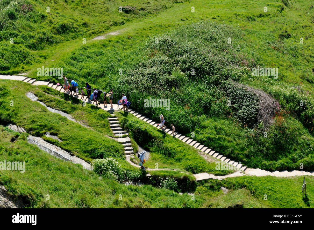 Path and steps between green hillsides at Mwnt beach with people Stock Photo