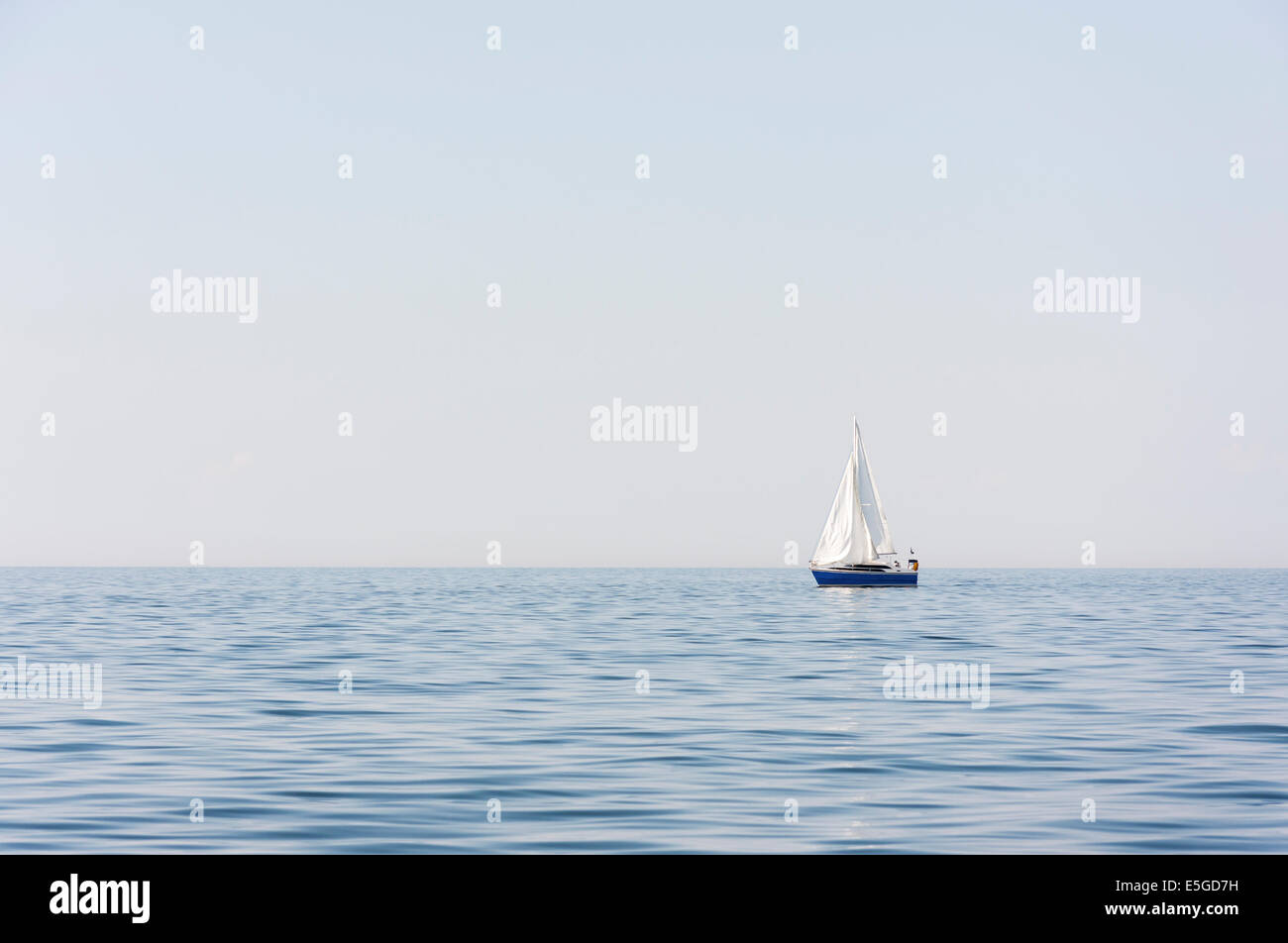 Blue sail ship with white sails at sea or ocean Stock Photo