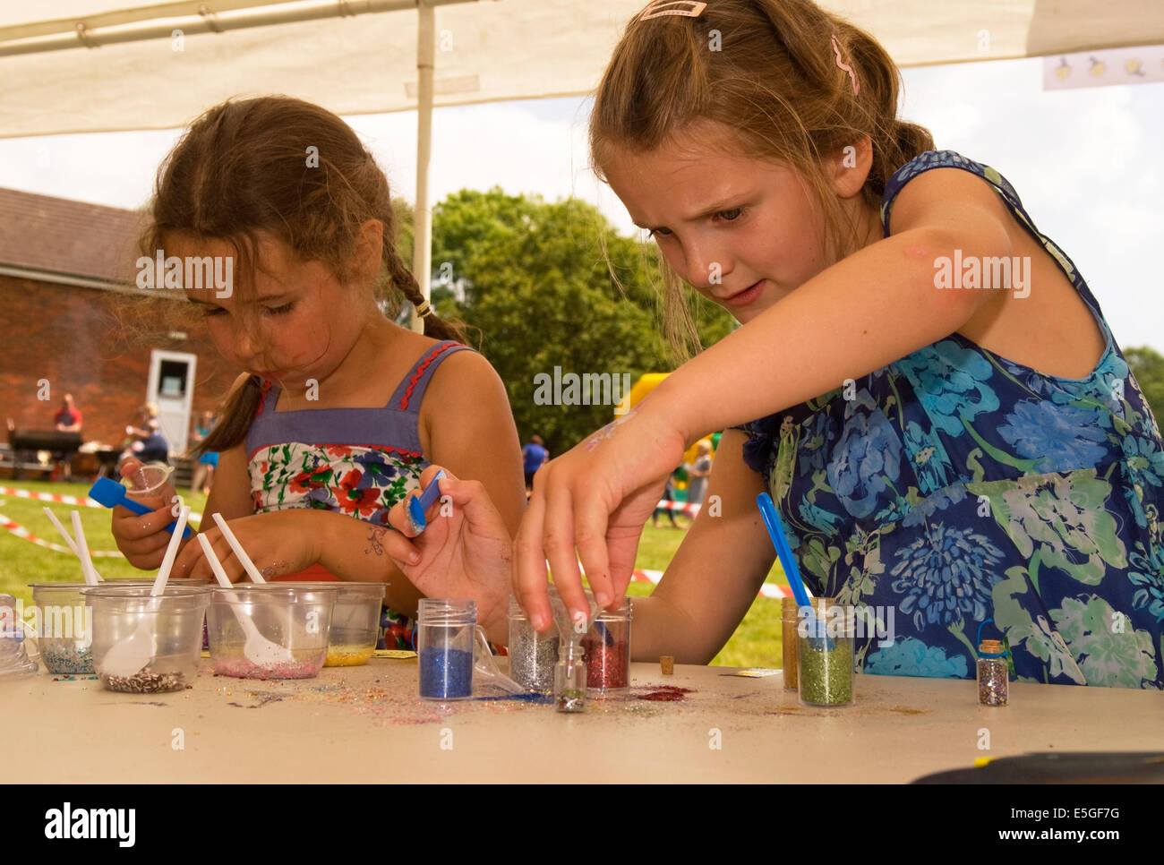 Two 6 year old girls mixing fairy dust at an annual summer fair, Rake, Hampshire, UK. Stock Photo