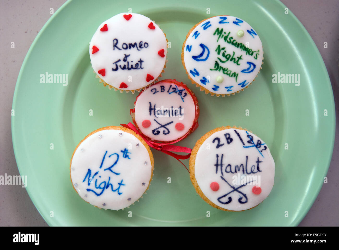 Cup cakes on a plate with the titles of some Shakespearean plays written in icing at a summer fair, Rake, Hampshire, UK. Stock Photo