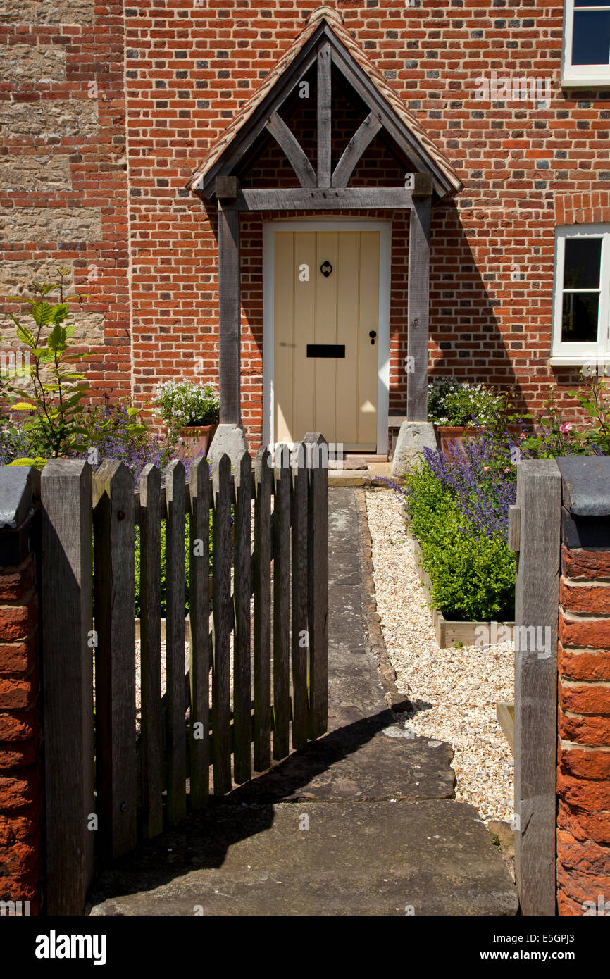 Wooden gate leading to front porch and doorway of English farmhouse with path and cottage garden Stock Photo