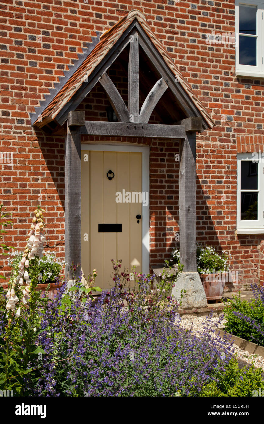 Front porch and doorway of English farmhouse with path and cottage garden Stock Photo
