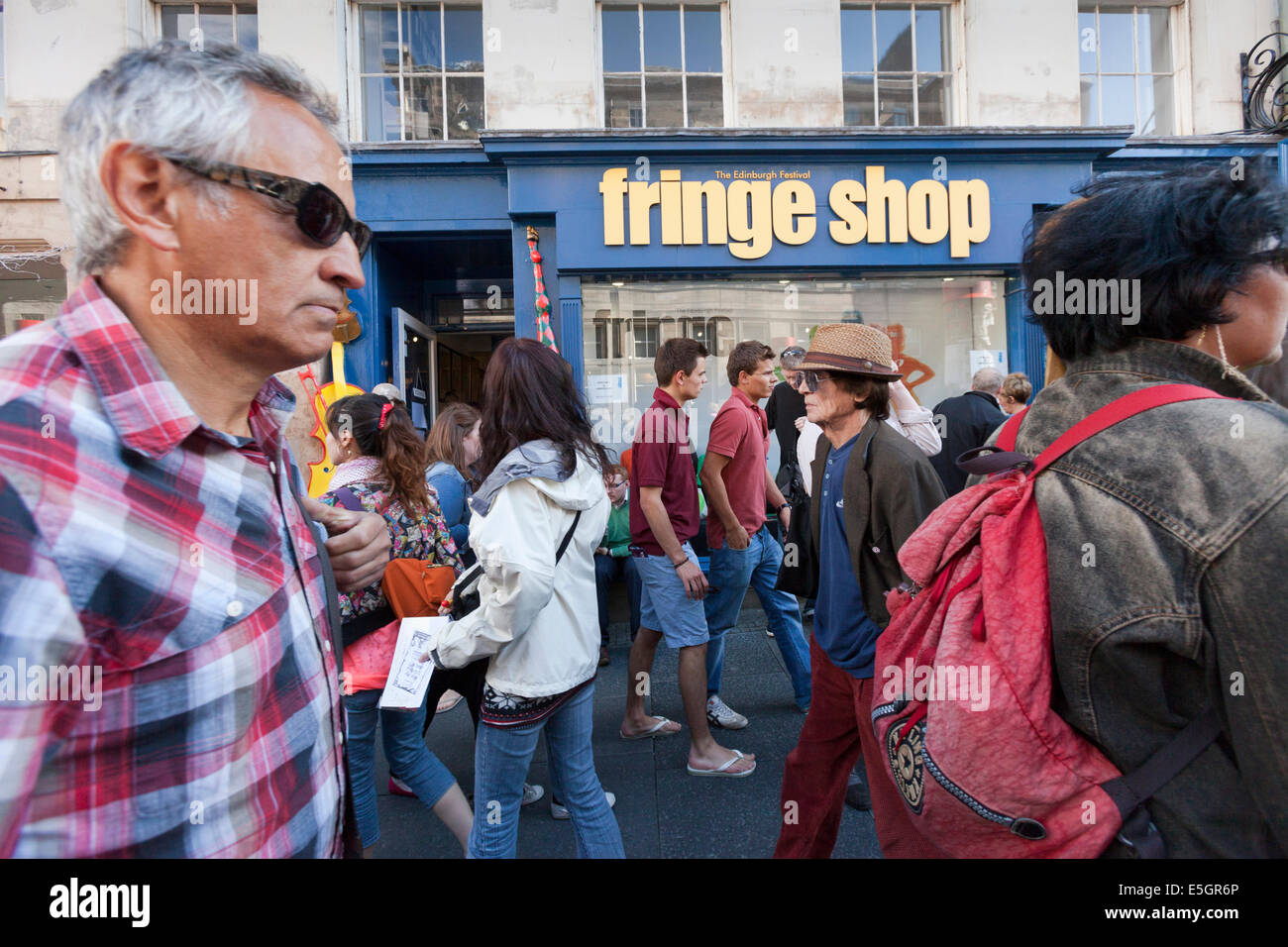 Festival visitors pass the Edinburgh Fringe shop in the city's High Street. Stock Photo