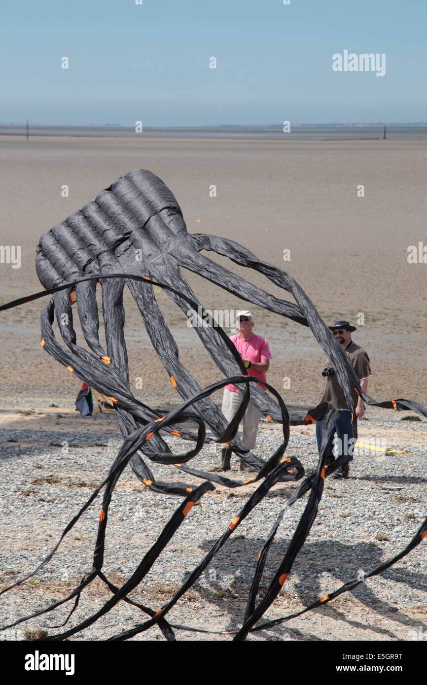 Man flying a black octopus kite on the beach at Morecambe Kite Festival Stock Photo