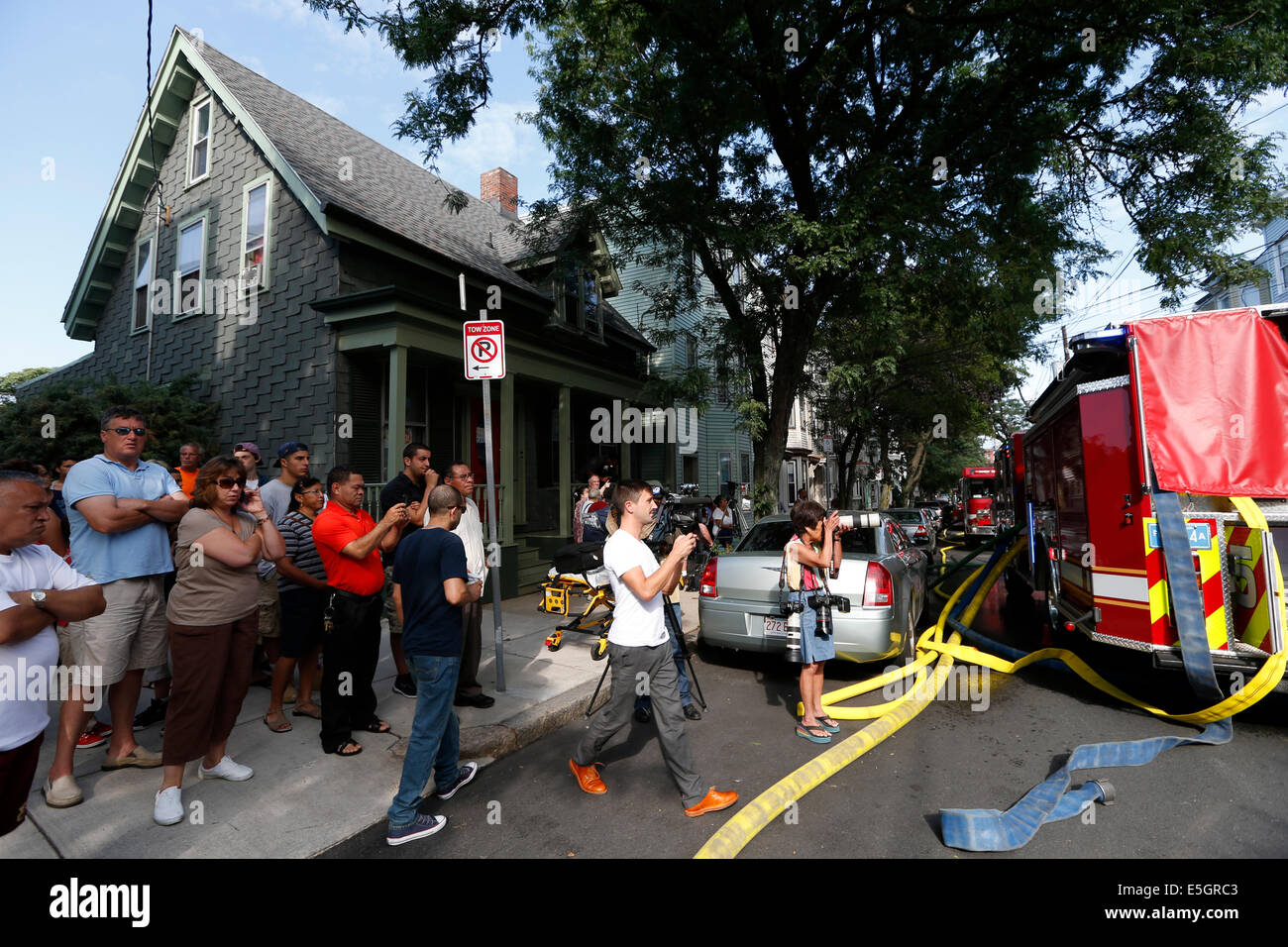 People gather to watch firefighters responding to a 6-alarm house fire in Boston, Massachusetts USA Stock Photo