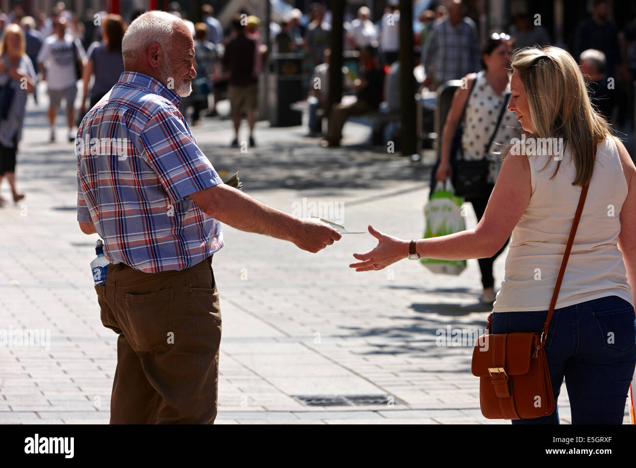 religious preacher handing out leaflets to woman in Belfast city centre northern ireland Stock Photo