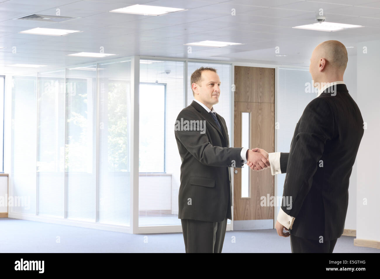 Two businessmen meeting in a brightly lit office space Stock Photo