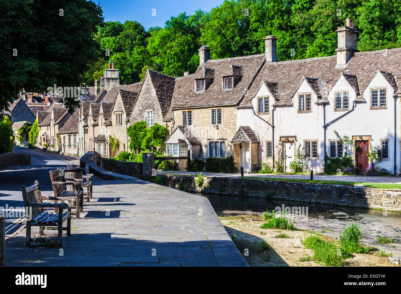 A row of pretty terraced cottages alongside the river Bybrook in the Cotswold village of Castle Combe in Wiltshire. Stock Photo